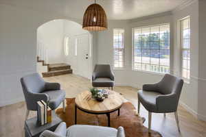Sitting room with crown molding, stairs, arched walkways, light wood finished floors, and baseboards