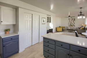 Kitchen featuring open floor plan, light wood-style floors, blue cabinetry, ceiling fan, and light countertops