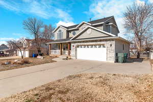 Traditional home with a garage, a porch, concrete driveway, and fence