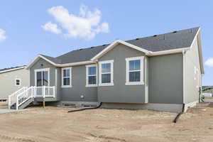 Back of property with roof with shingles and stucco siding
