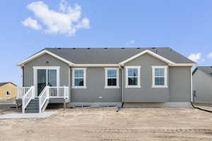 Back of property featuring roof with shingles and stucco siding
