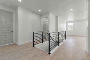 Corridor featuring an upstairs landing, light wood finished floors, and recessed lighting