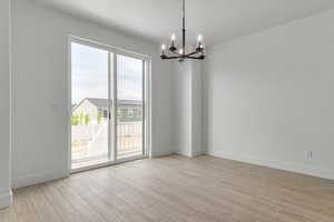 Unfurnished room featuring a chandelier and light wood-style floors