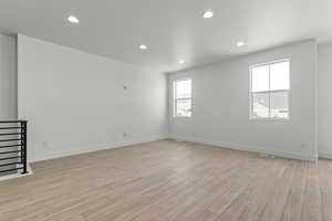Unfurnished room featuring light wood-style flooring, recessed lighting, and stairway
