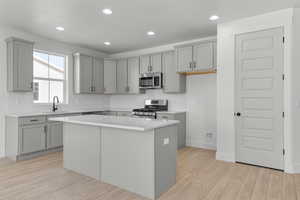 Kitchen featuring appliances with stainless steel finishes, gray cabinets, light wood-style flooring, tasteful backsplash, and recessed lighting