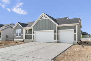View of front facade with board and batten siding, an attached garage, concrete driveway, and roof with shingles
