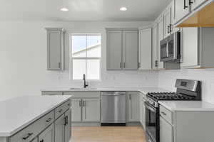 Kitchen featuring appliances with stainless steel finishes, gray cabinetry, recessed lighting, light countertops, and tasteful backsplash