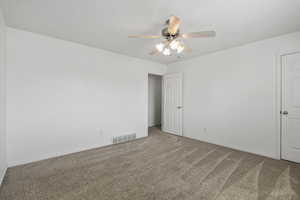 Spare room with visible vents, carpet flooring, baseboards, and ceiling fan