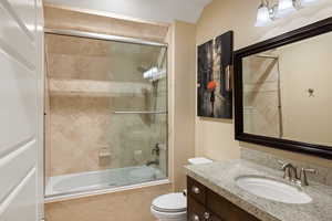 Full bathroom featuring tiled shower / bath combo, vanity, and toilet