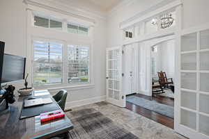 Office space featuring arched walkways, crown molding, french doors, a towering ceiling, and baseboards