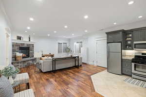 Living area with ornamental molding, wood finished floors, a stone fireplace, recessed lighting, and baseboards