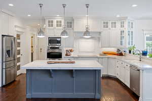 Kitchen with appliances with stainless steel finishes, a sink, dark wood-style floors, white cabinets, and recessed lighting