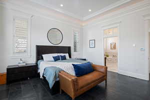 Bedroom featuring a tray ceiling, ornamental molding, recessed lighting, ensuite bathroom, and baseboards