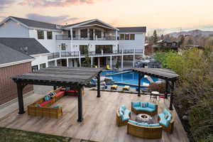 Rear view of house with an outdoor living space with a fire pit, an outdoor pool, a balcony, a mountain view, and a gazebo