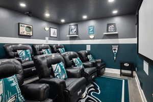 Home theater featuring wood finished floors, recessed lighting, and baseboards