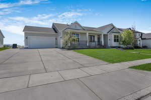 Ranch-style home featuring concrete driveway, a front lawn, board and batten siding, covered porch, and a garage
