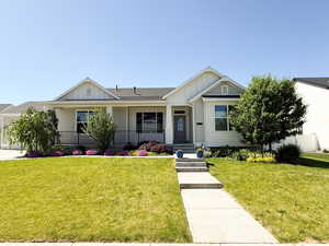 View of front of house featuring board and batten siding, covered porch, a front lawn, and an attached garage