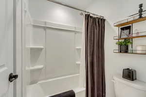 Full bath featuring shower / bath combo with shower curtain and toilet