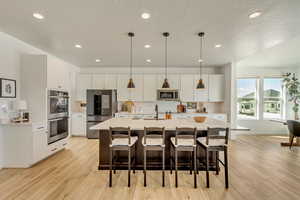 Kitchen with appliances with stainless steel finishes, light wood finished floors, and light countertops