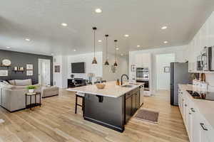 Kitchen with open floor plan, light wood-style flooring, stainless steel appliances, and a sink