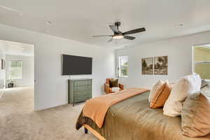 Bedroom featuring light carpet, baseboards, ceiling fan, and multiple windows