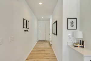 Hall with recessed lighting, light wood finished floors, and baseboards