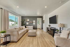 Living room with recessed lighting, light wood-style flooring, and baseboards
