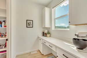 Kitchen featuring white cabinets, light countertops, visible vents, light wood-style floors, and baseboards