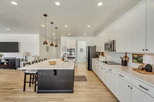 Kitchen featuring light wood finished floors, a kitchen breakfast bar, stainless steel appliances, and a sink