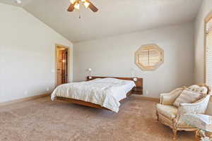 Bedroom featuring ceiling fan, lofted ceiling, baseboards, and light carpet