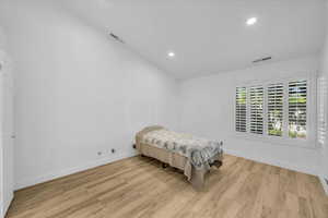 Bedroom with visible vents, light wood finished floors, and baseboards