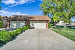 View of front of house featuring concrete driveway, a front lawn, a garage, brick siding, and roof with shingles