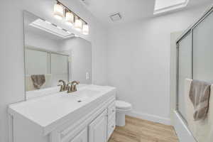 Full bath with wood finished floors, vanity, baseboards, toilet, and visible vents