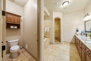Bathroom featuring a sink, a bath, stone tile flooring, a tile shower, and toilet