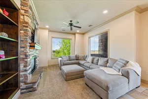 Carpeted living area featuring recessed lighting, crown molding, a fireplace, a textured ceiling, and ceiling fan