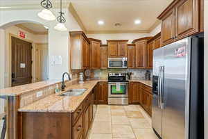 Kitchen with brown cabinets, visible vents, a sink, crown molding, and appliances with stainless steel finishes