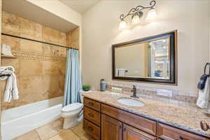 Bathroom with shower / bath combination with curtain, toilet, and vanity