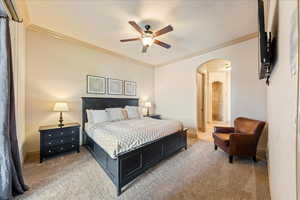 Bedroom featuring arched walkways, crown molding, and light colored carpet