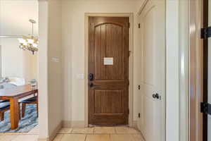 Doorway to outside with baseboards and a notable chandelier