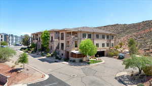View of building exterior featuring a garage, uncovered parking, and a mountain view