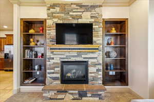 Living area featuring crown molding, tile patterned flooring, and a stone fireplace