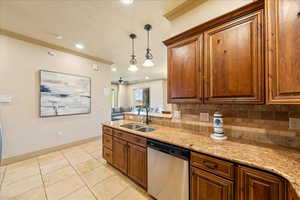 Kitchen with stainless steel dishwasher, a sink, crown molding, tasteful backsplash, and hanging light fixtures