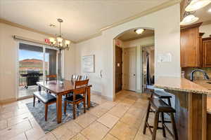 Dining space with arched walkways, baseboards, visible vents, an inviting chandelier, and crown molding