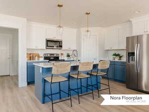 Kitchen featuring a breakfast bar area, a sink, stainless steel appliances, and light wood-type flooring
