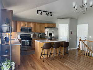 Kitchen with light countertops, wood finished floors, rail lighting, and appliances with stainless steel finishes