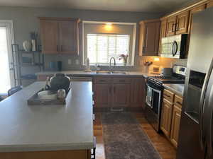 Kitchen with light wood-style flooring, a center island, stainless steel appliances, and a sink