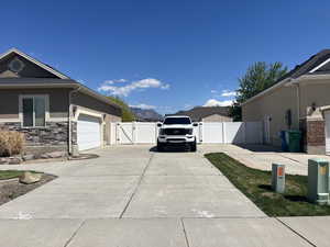 View of side of home with a gate, driveway, fence, an attached garage, and stucco siding