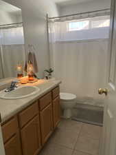 Full bathroom featuring vanity, toilet, tile patterned flooring, and a shower.