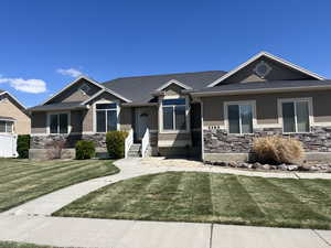 Craftsman house with stone siding, a front lawn, and stucco siding