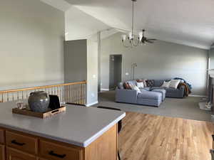 Kitchen with light wood-style floors, vaulted ceiling, baseboards, and an inviting chandelier
